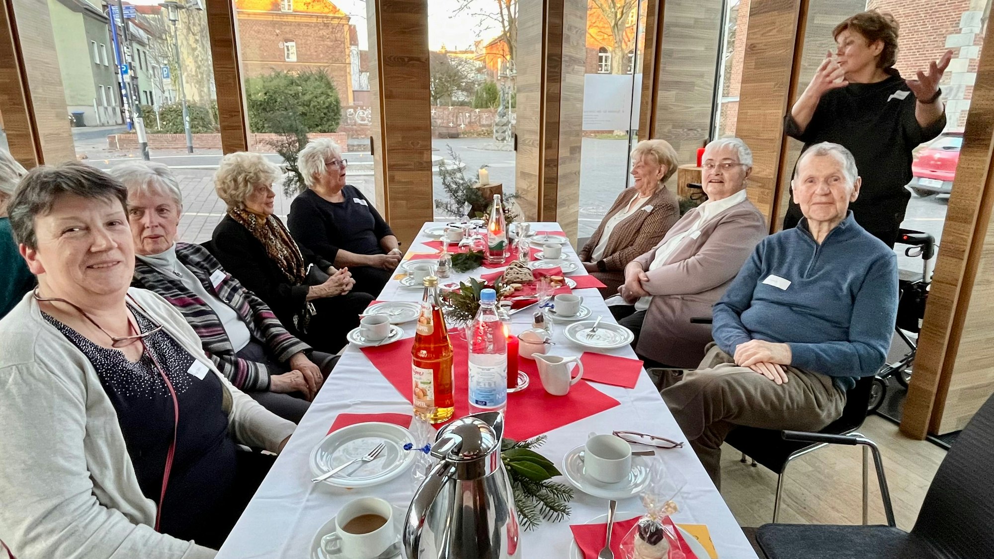 Zu sehen sind Frauen und Männer an einer gedeckten Tafel.