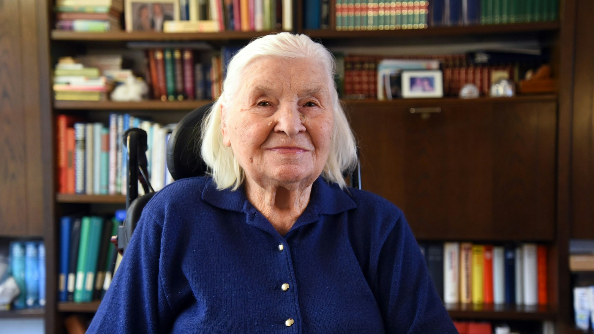Eine alte Dame vor einem Bücherregal.