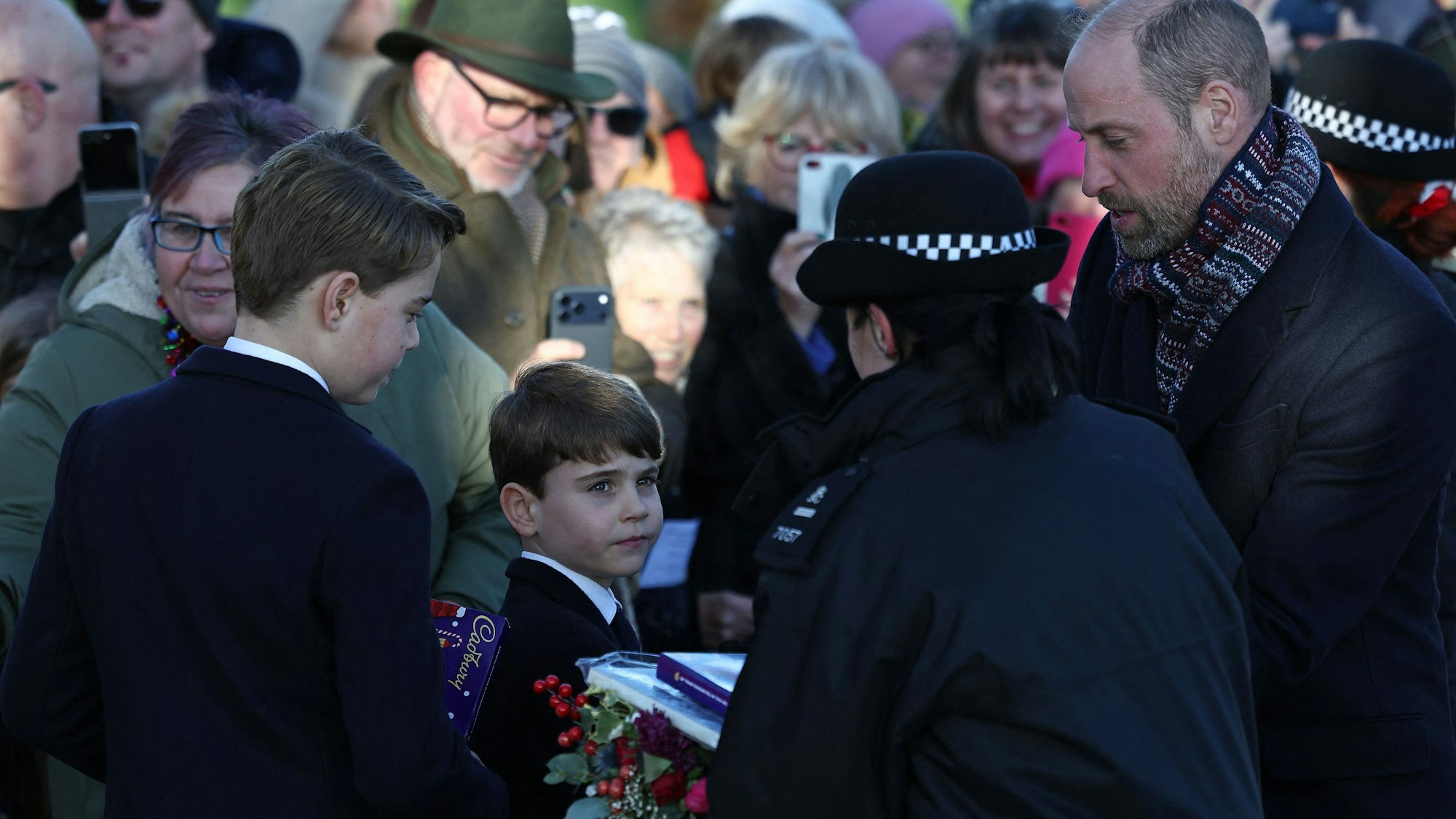 Eine Polizistin nimmt die Geschenke entgegen, die Gratulanten nach dem Weihnachtsgottesdienst in Sandringham an Prinz George, Prinz Louis und Prinz William überreichten.
