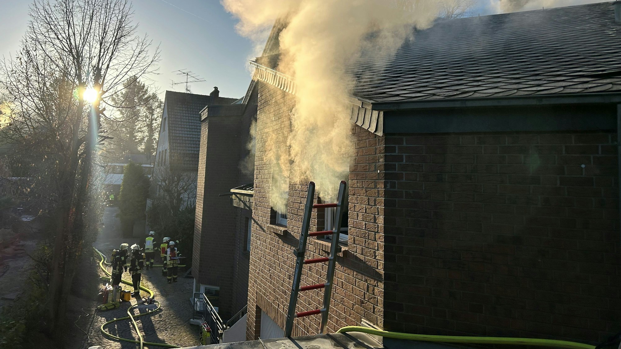 Es qualmt aus einem Fenster. Feuerwehrleute sind im Einsatz.