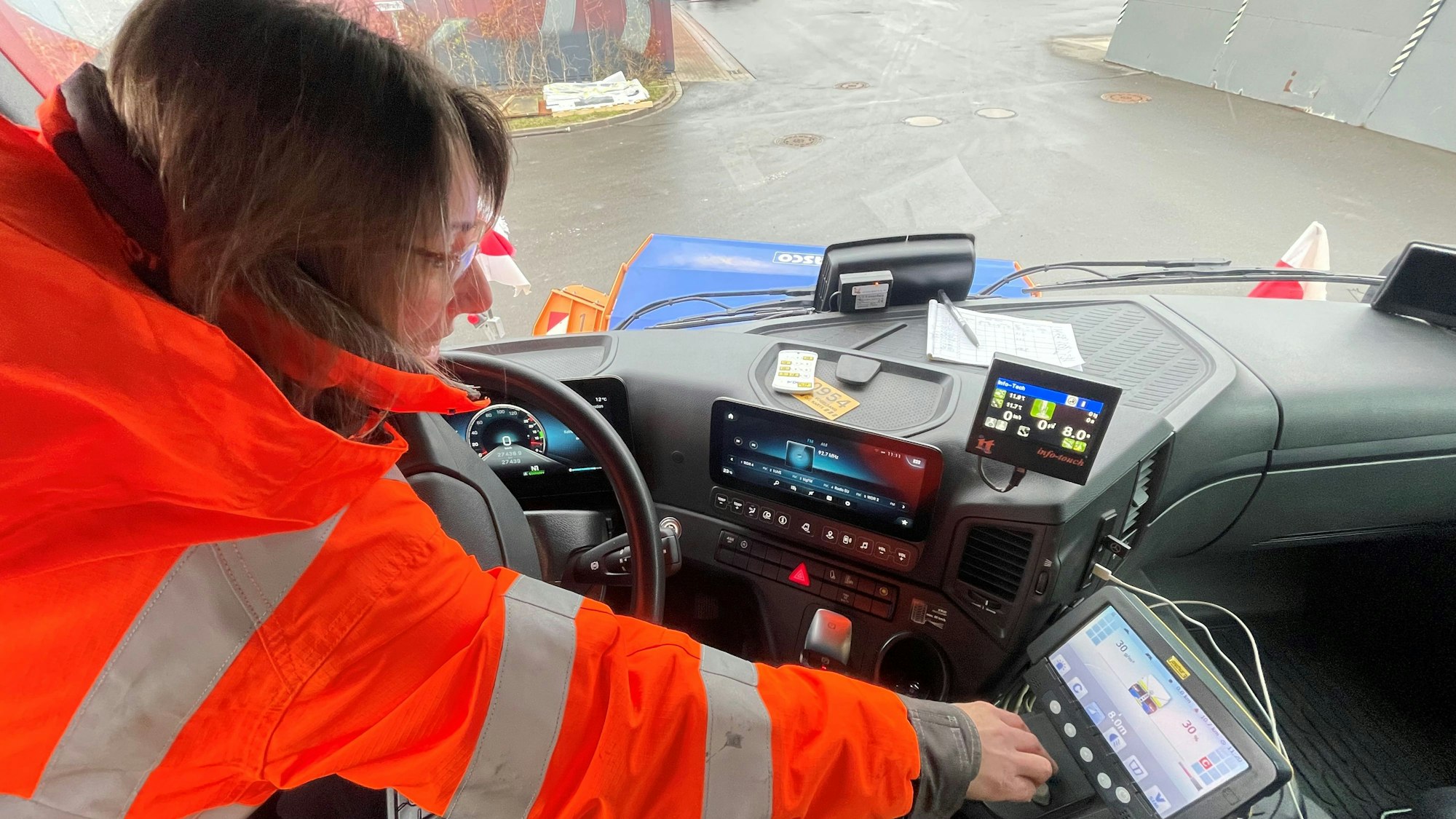Eva Heinen sitzt am Steuer eines Räumfahrzeugs und bedient digitale Kontrollen.