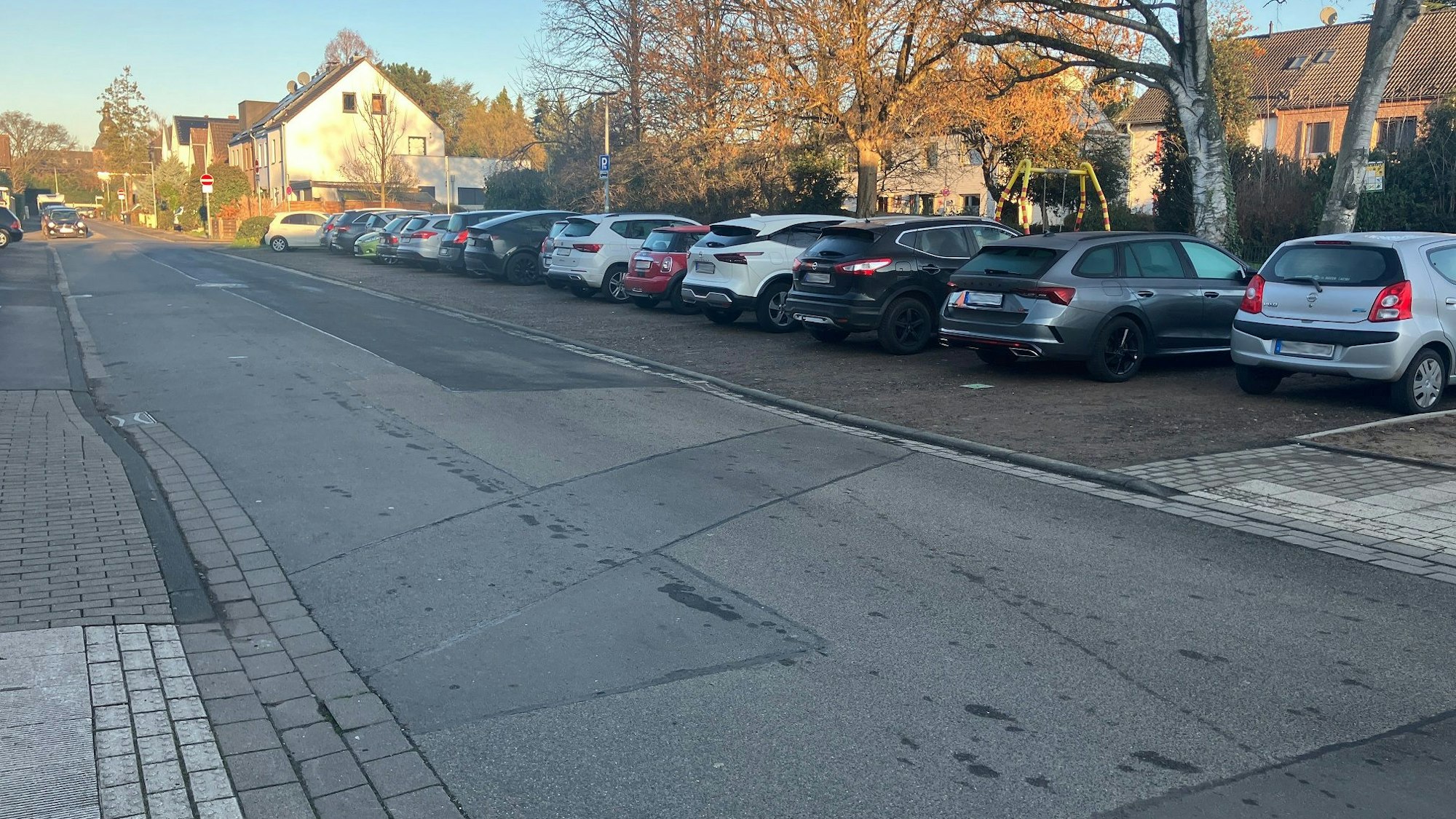 Eine Straße, an der rechten Seite parken Autos.