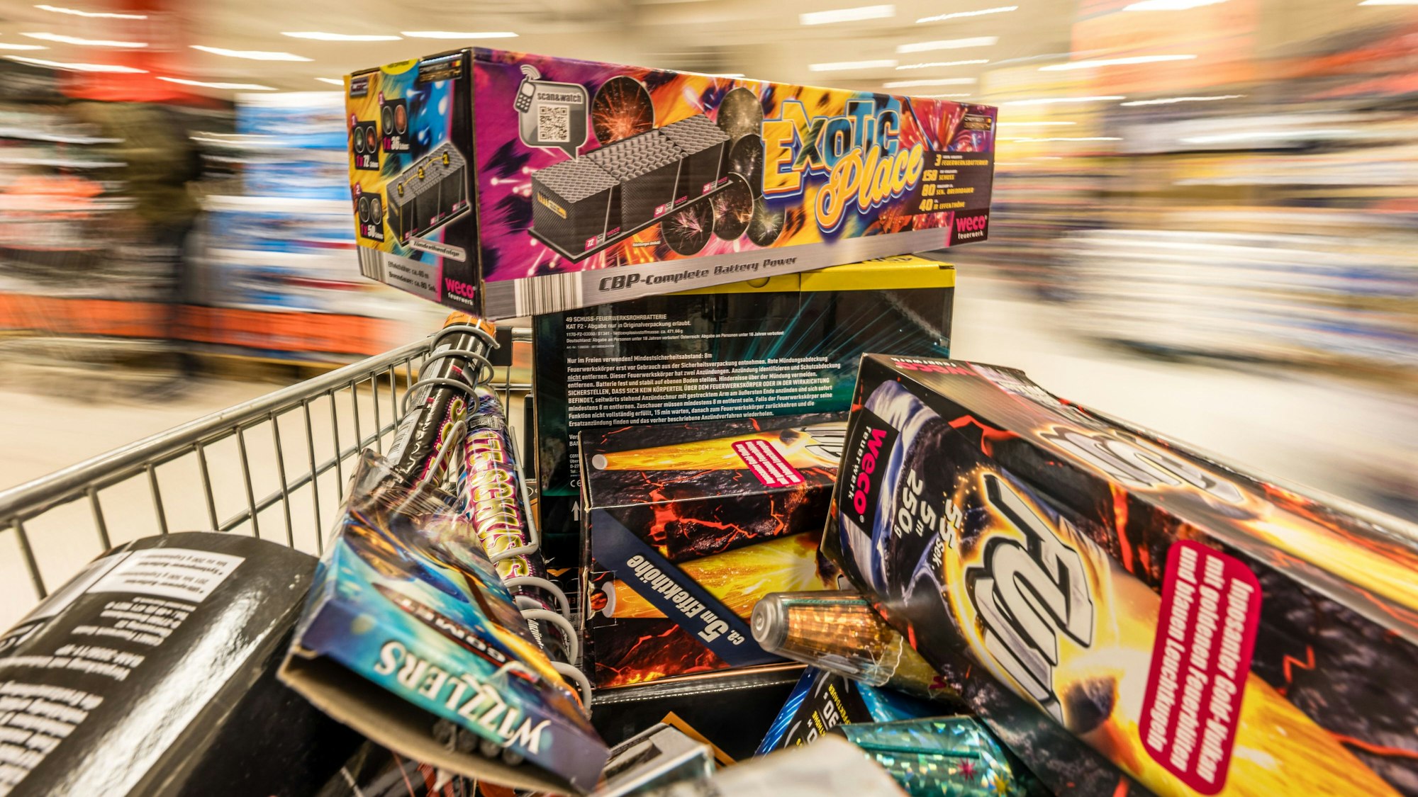 Ein Einkaufswagen mit Feuerwerk wird durch einen Supermarkt geschoben.