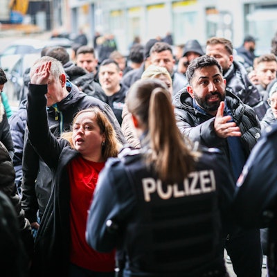 Aufgebrachte Kunden diskutieren vor der Sparkassenfiliale in Buer mit Polizeibeamten nach der Räumung des Vorraums der Filiale.