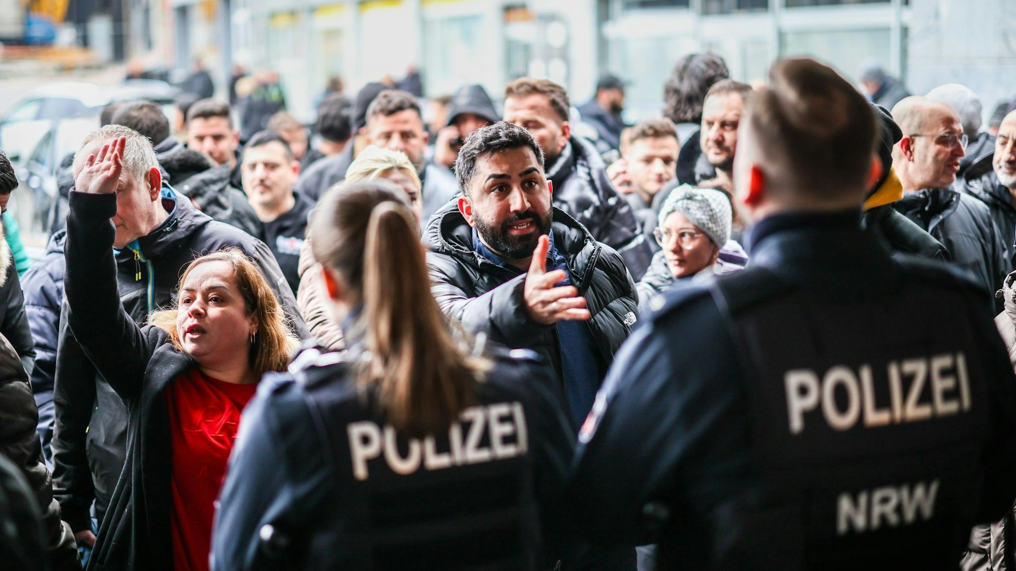 Aufgebrachte Kunden diskutieren vor der Sparkassenfiliale in Buer mit Polizeibeamten nach der Räumung des Vorraums der Filiale.