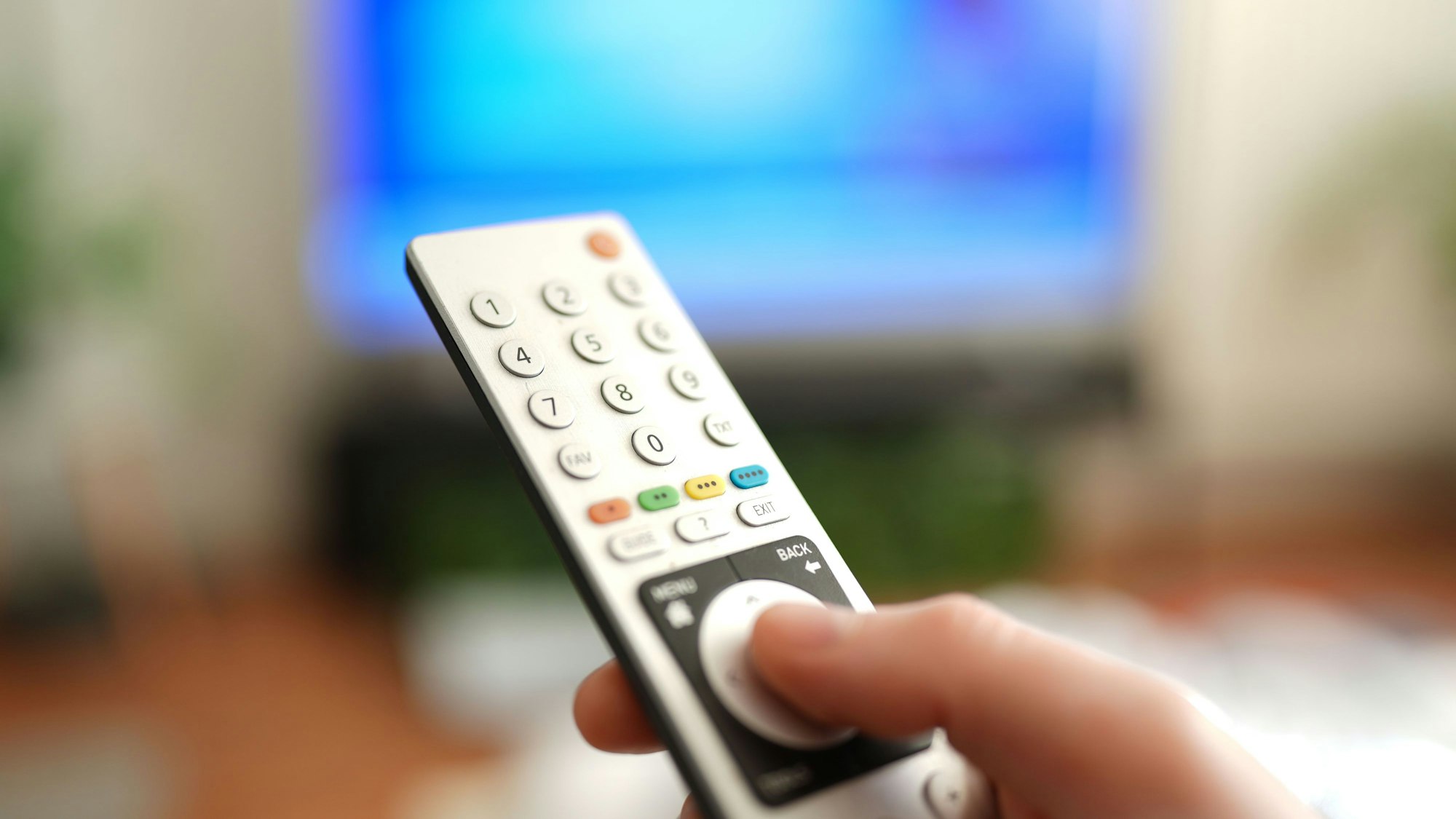 Ein Mann drückt einen Knopf auf der Fernbedienung seines Fernsehers.