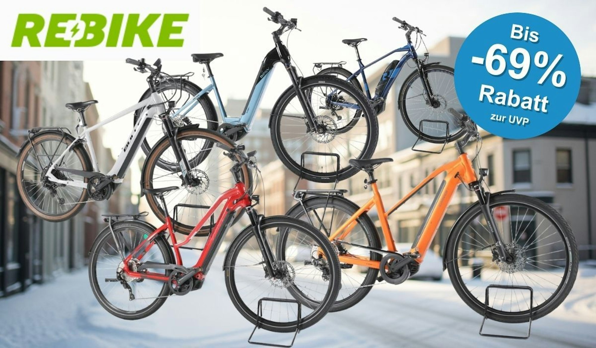 E-Bikes Trekking, City und E-Mountain-Bikes verschiedener Marken vor einer verschneiten Innenstadt.