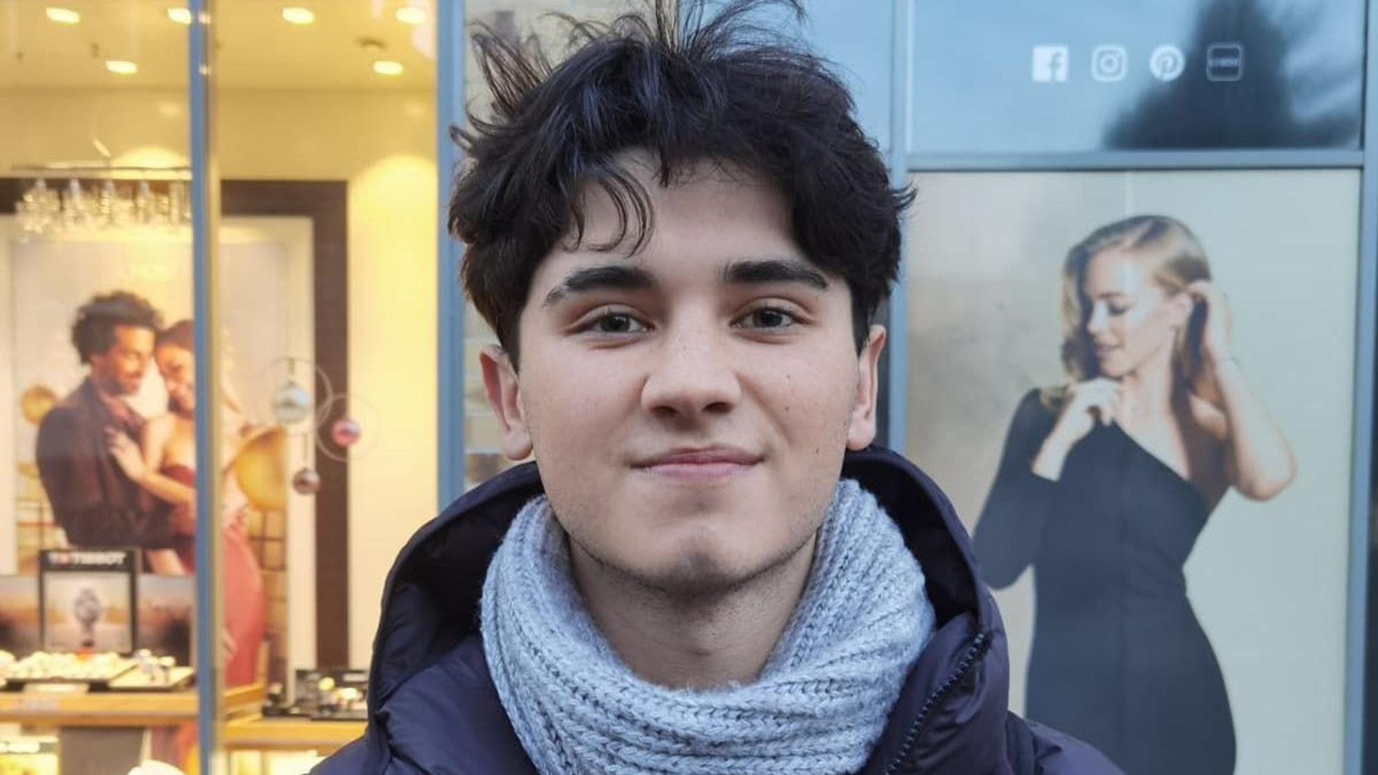 Ein junger Mann schaut leicht lächelnd in die Kamera.