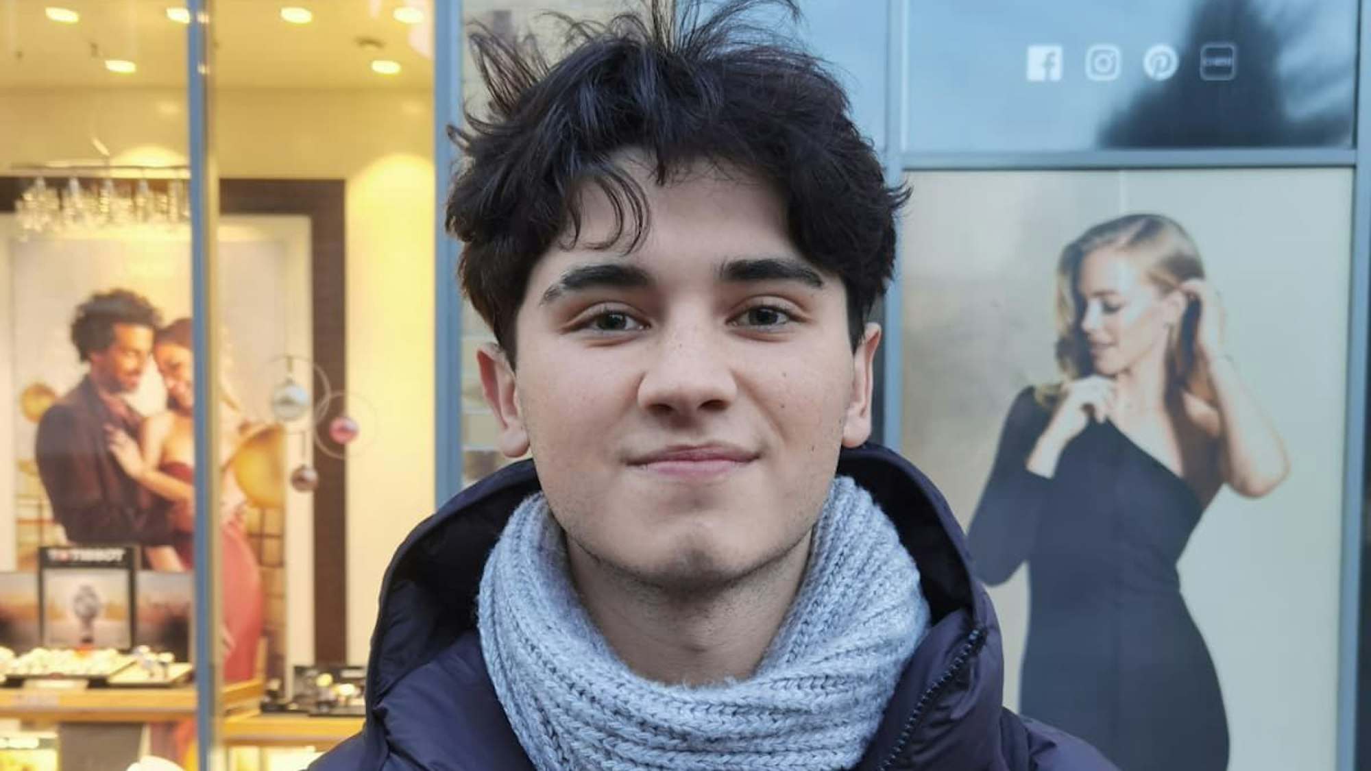 Ein junger Mann schaut leicht lächelnd in die Kamera.