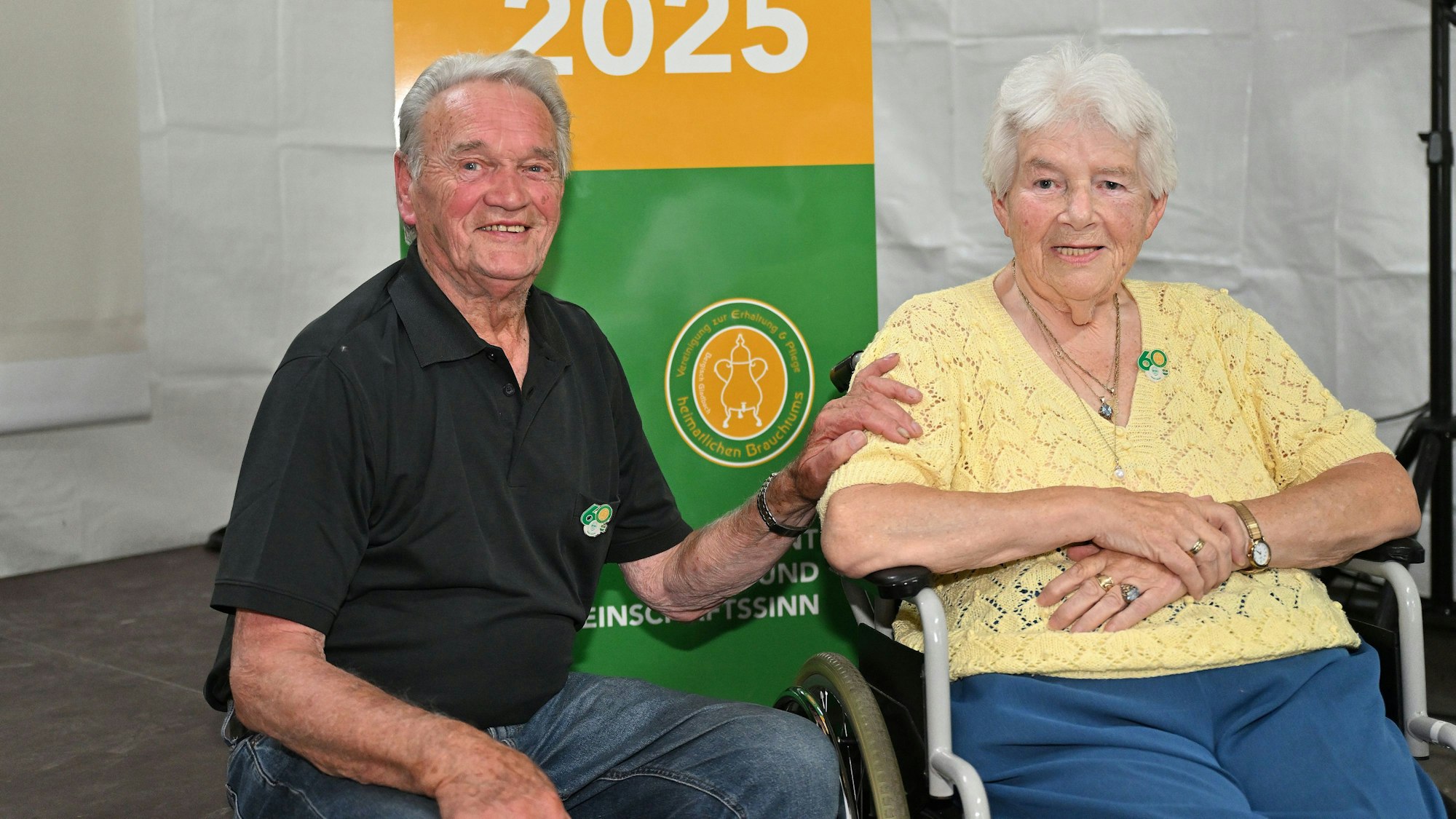 Ein älterer Mann und eine ältere Frau schauen in die Kamera und lächeln.