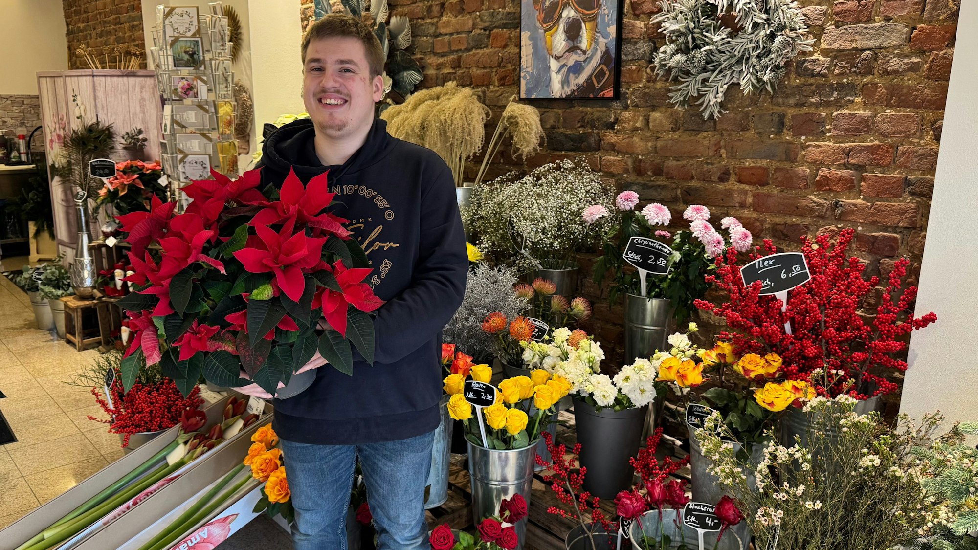 Auf dem Bild ist ein junger Mann in seinem Blumenladen zu sehen.