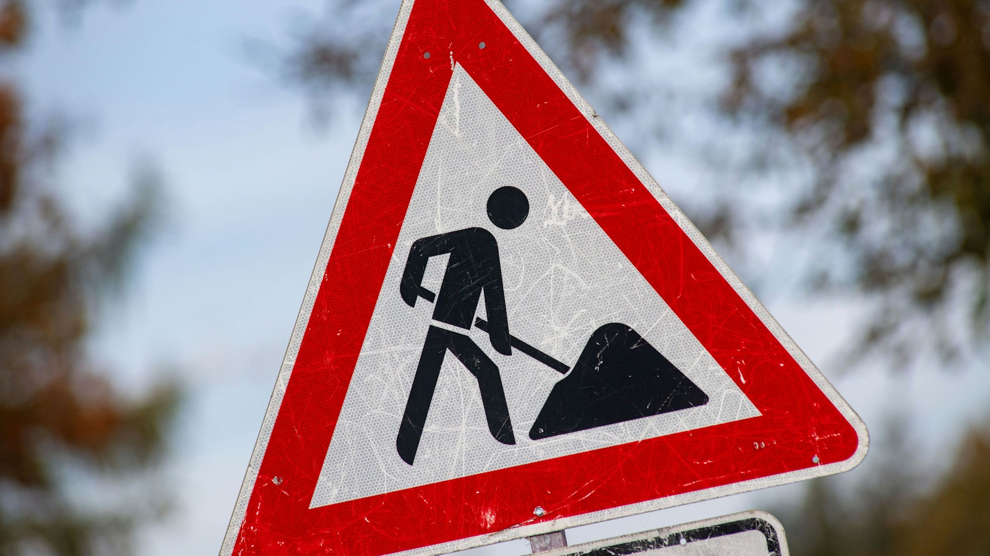 Das Foto zeigt ein zerkratztes Schild mit dem Piktogramm eines Bauarbeiters zur Beschilderung einer Baustelle.