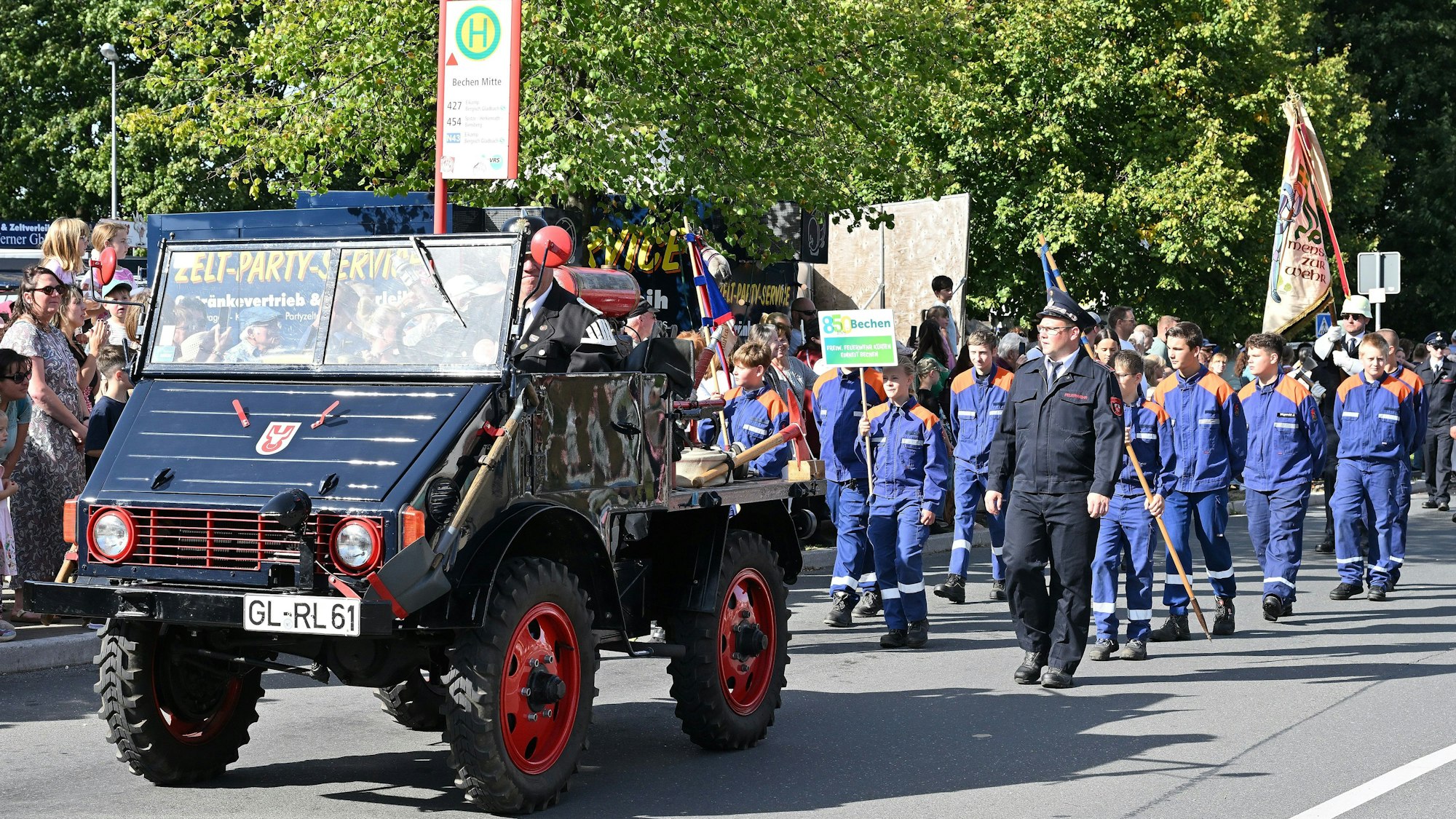 Viele Menschen marschieren im Gleichschritt mit Fahnen zur Jubiläumsfeier von Bechen.