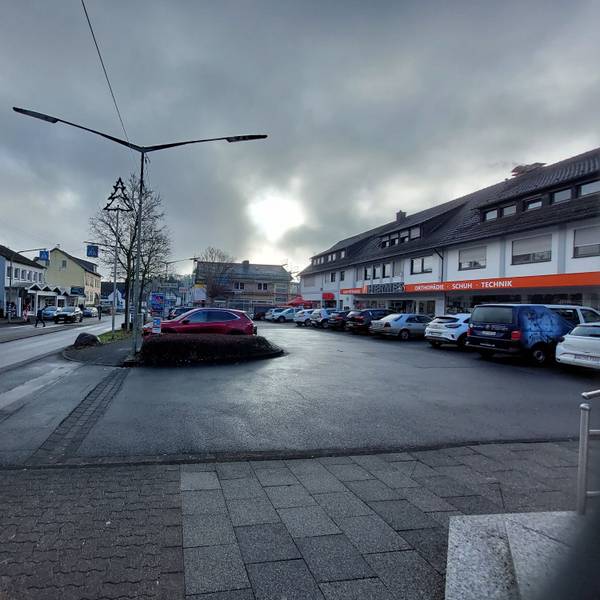 Autos auf dem Parkplatz vor einer Ladenzeile.
