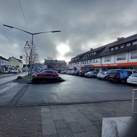 Autos auf dem Parkplatz vor einer Ladenzeile.