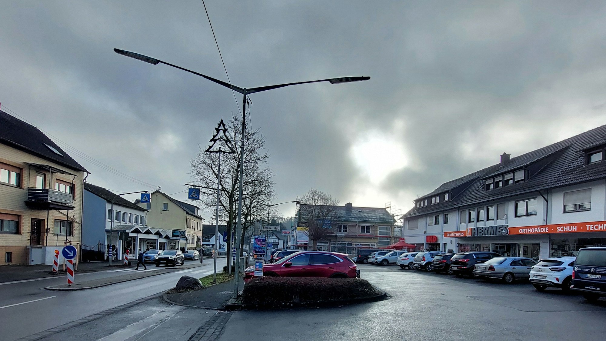 Autos auf dem Parkplatz vor einer Ladenzeile.