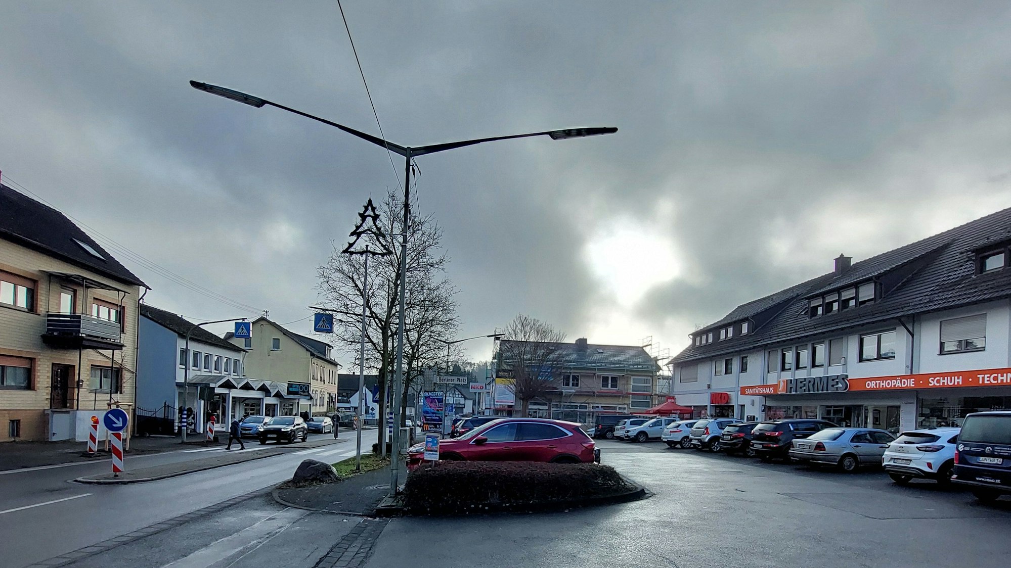 Autos auf dem Parkplatz vor einer Ladenzeile.