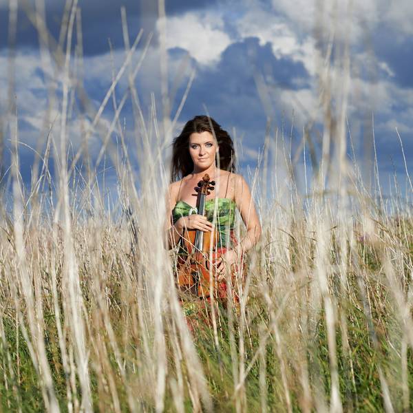 Anna-Liisa Bezrodny steht in einem Feld zwischen hohen Grashalmen.