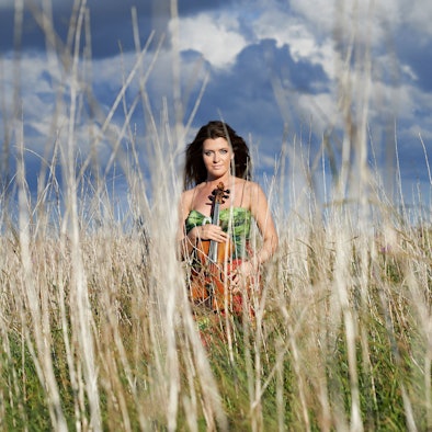 Anna-Liisa Bezrodny steht in einem Feld zwischen hohen Grashalmen.