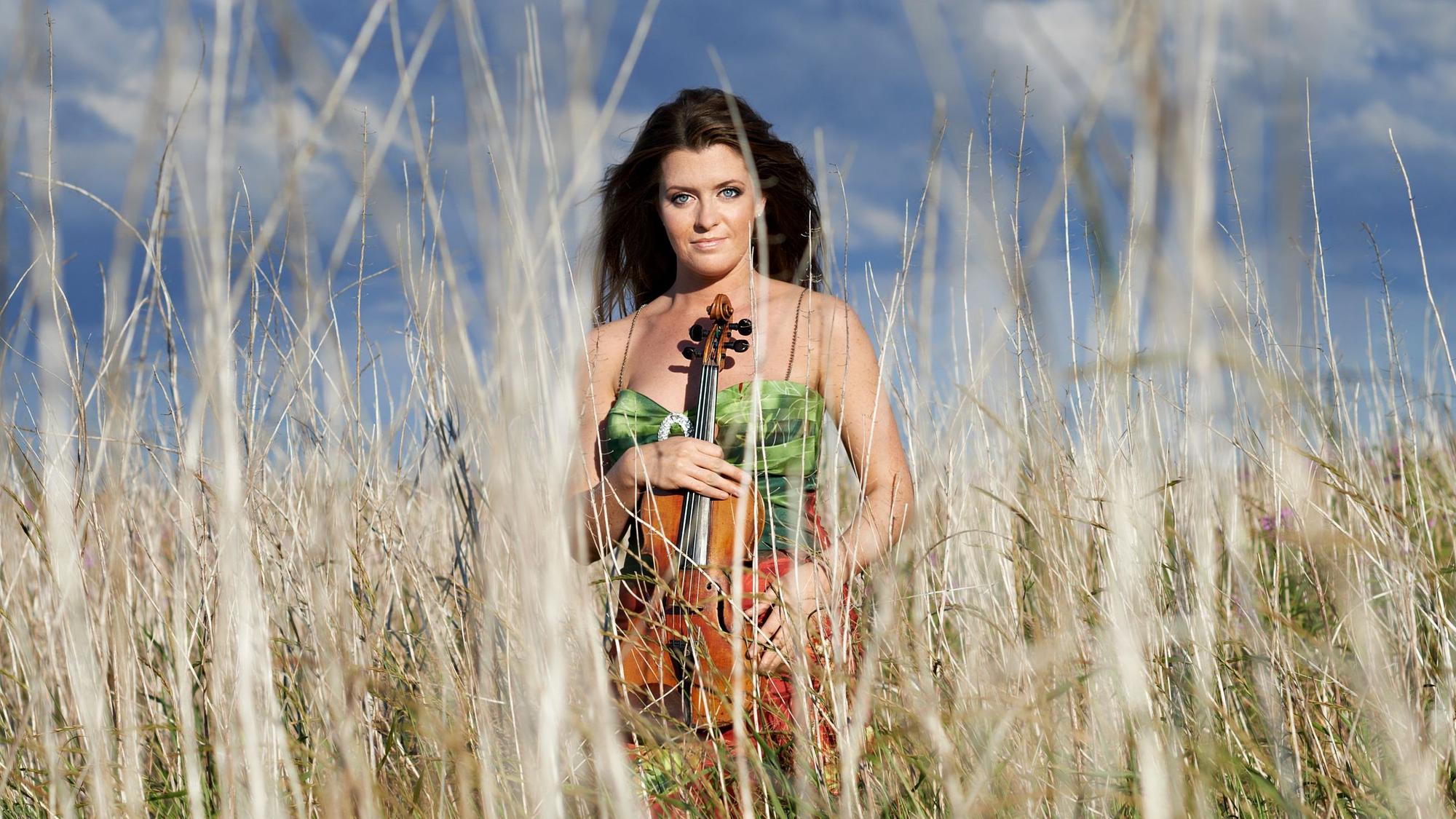 Anna-Liisa Bezrodny steht in einem Feld zwischen hohen Grashalmen.