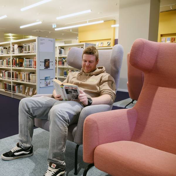 Bibliothekschef Christian Bürgin sitzt in einem Sessel und liest ein Buch.