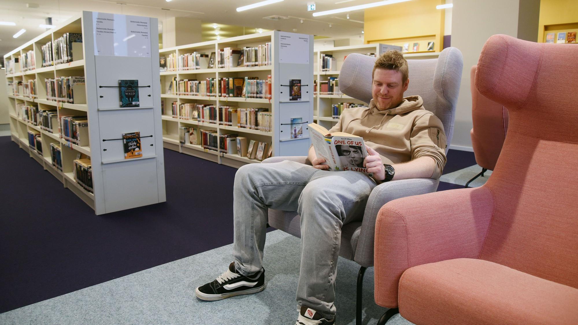 Bibliothekschef Christian Bürgin sitzt in einem Sessel und liest ein Buch.