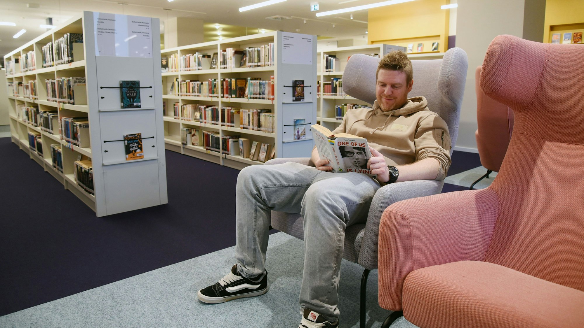 Bibliothekschef Christian Bürgin sitzt in einem Sessel und liest ein Buch.