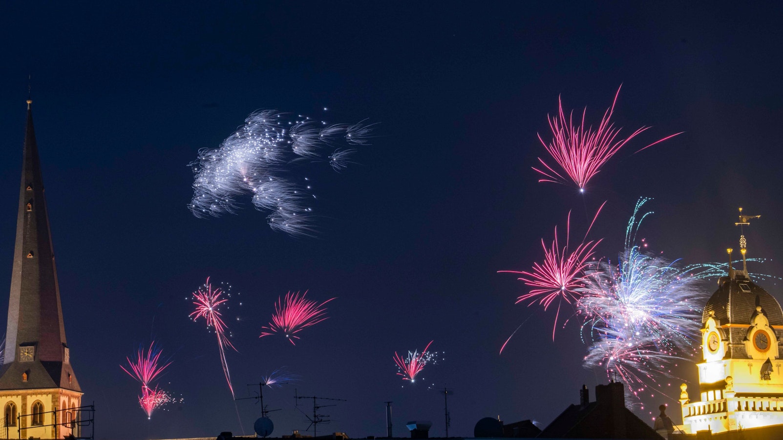 Das Bild zeigt die erleuchtete Martinskirche. Auch das Alte Rathaus ist erleuchtet. Zwischen den Gebäuden explodieren Feuerwerksraketen.