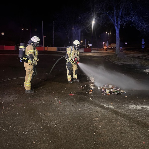Zwei Feuerwehrleute löschen Feuerwerksmüll.