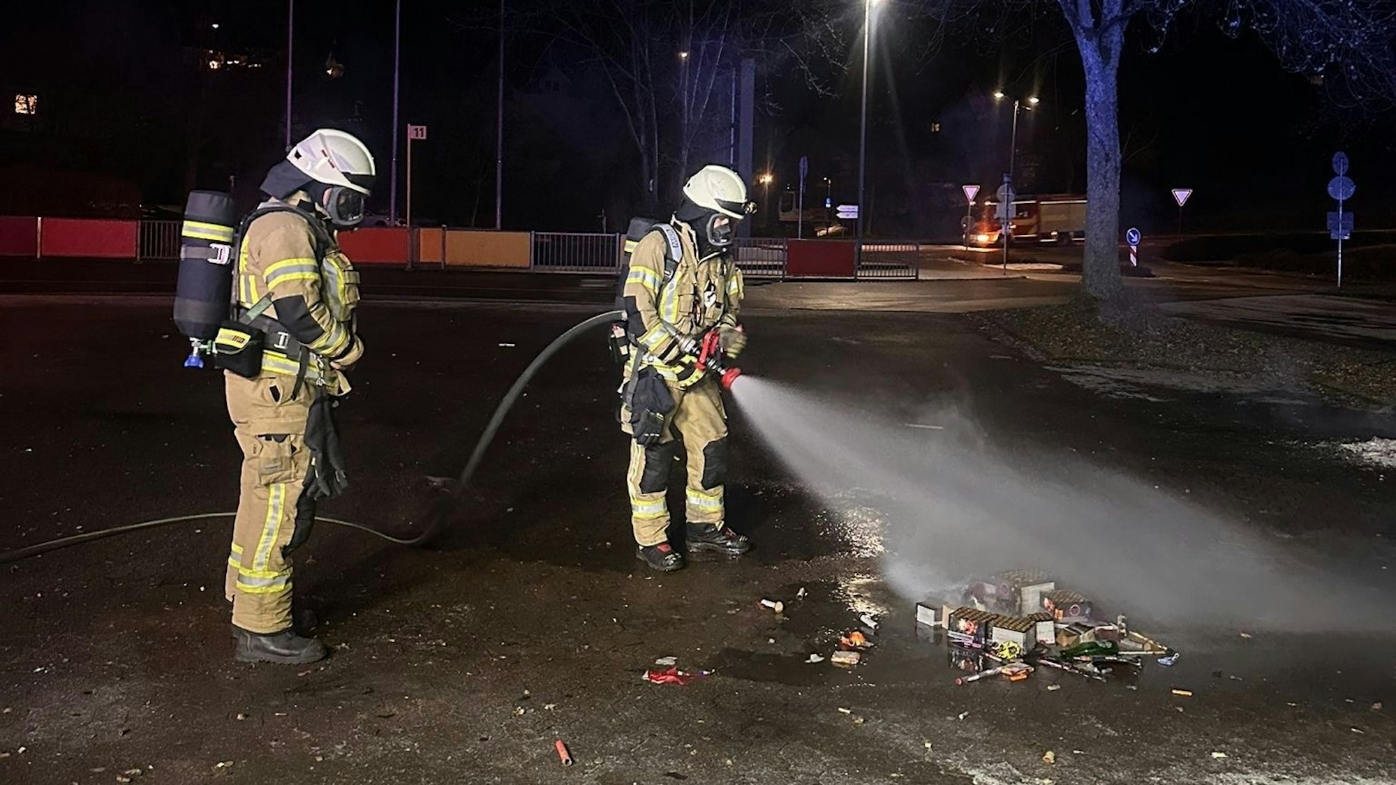Zwei Feuerwehrleute löschen Feuerwerksmüll.