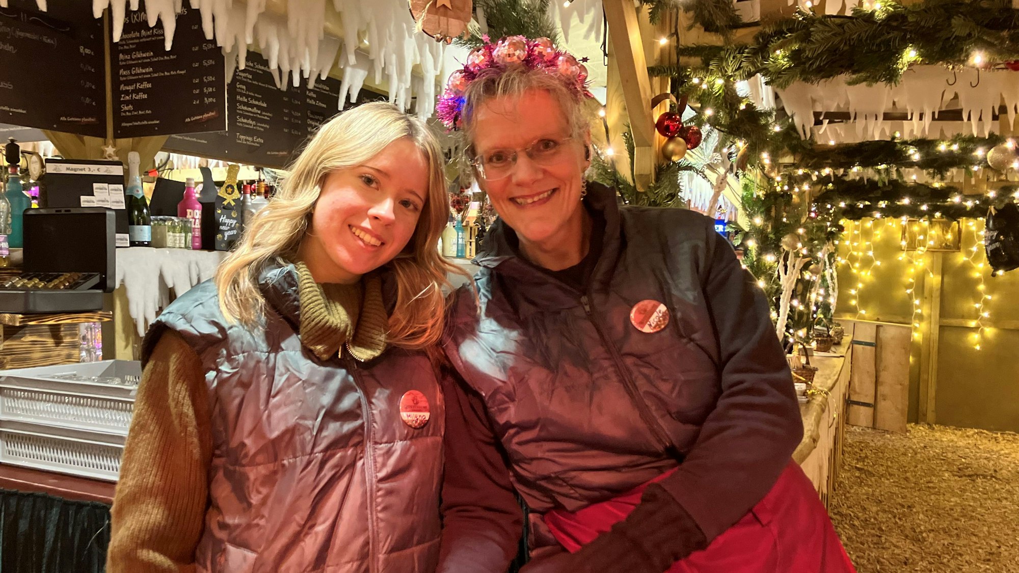 Zwei Kellnerinnen stehen an einem Tresen in einem Winterdorf zusammen.