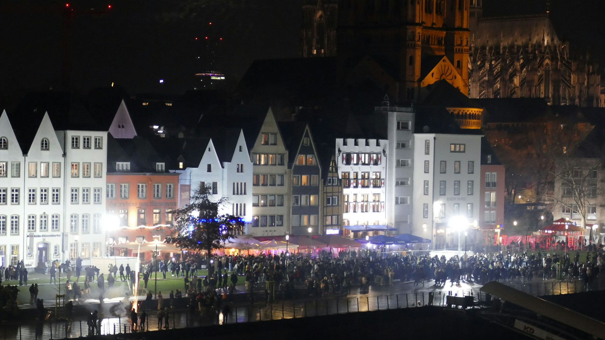 31.12.2025: Menschen stehen gegen 23 Uhr am Kölner Rheinufer, das sich stetig füllt.
