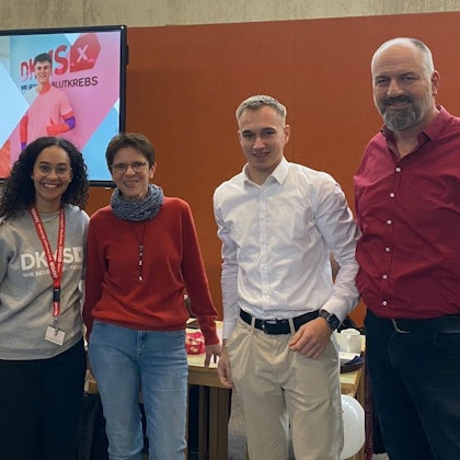 Salome Steinhoff, Birgit Karsten, Tim Förster und Klaus Drotbohm stehen nebeneinander. Links hinter ihnen ist ein Plakat der DKMS zu sehen.