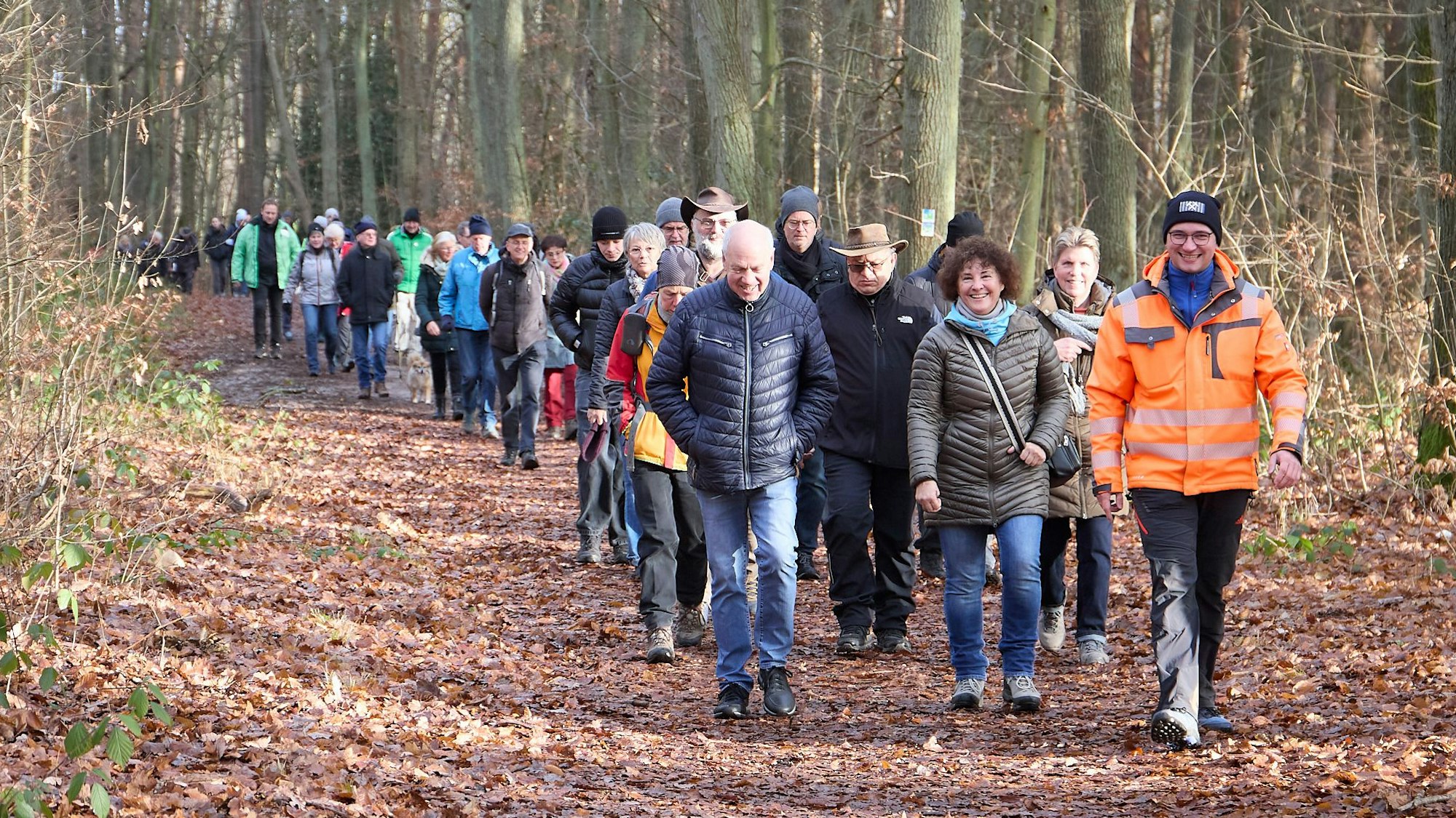 Eine große Gruppe Menschen geht durch den winterlichen Wald.