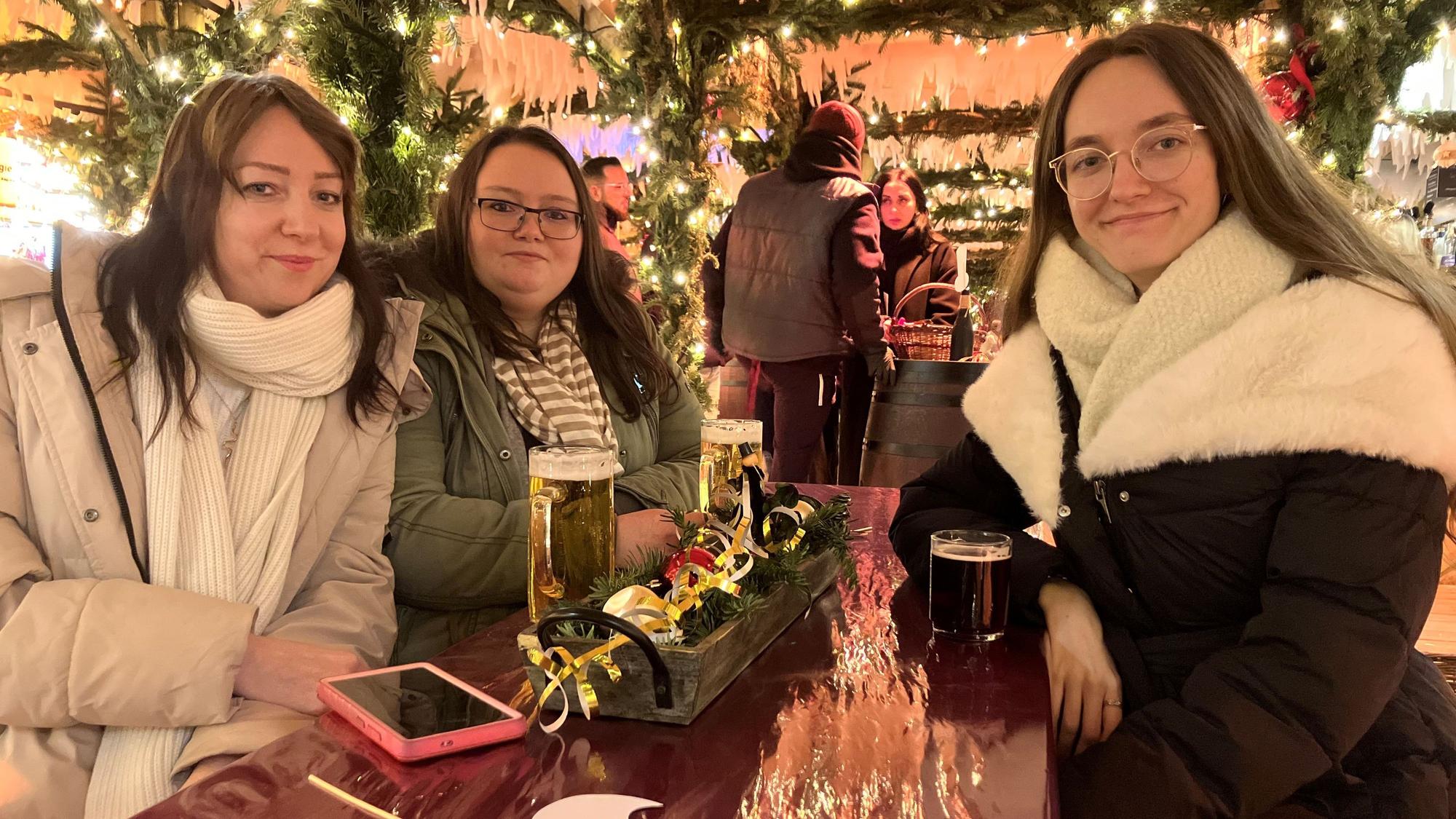 Im Winterdorf sitzen die Schwestern Christina (r.) und Veronika Janzen mit ihrer Freundin Elena Beck (M.) an einem Tisch.