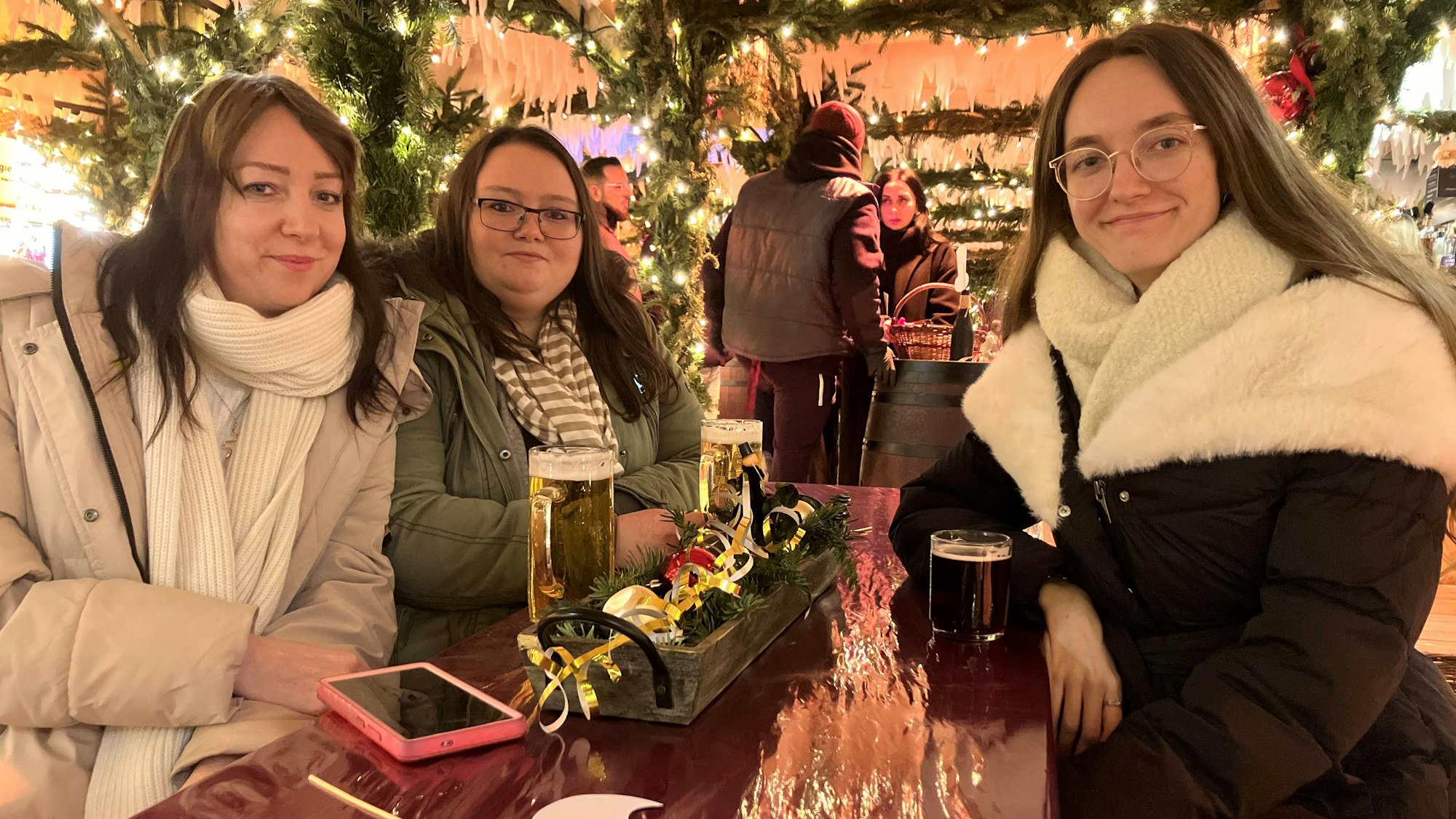 Im Winterdorf sitzen die Schwestern Christina (r.) und Veronika Janzen mit ihrer Freundin Elena Beck (M.) an einem Tisch.