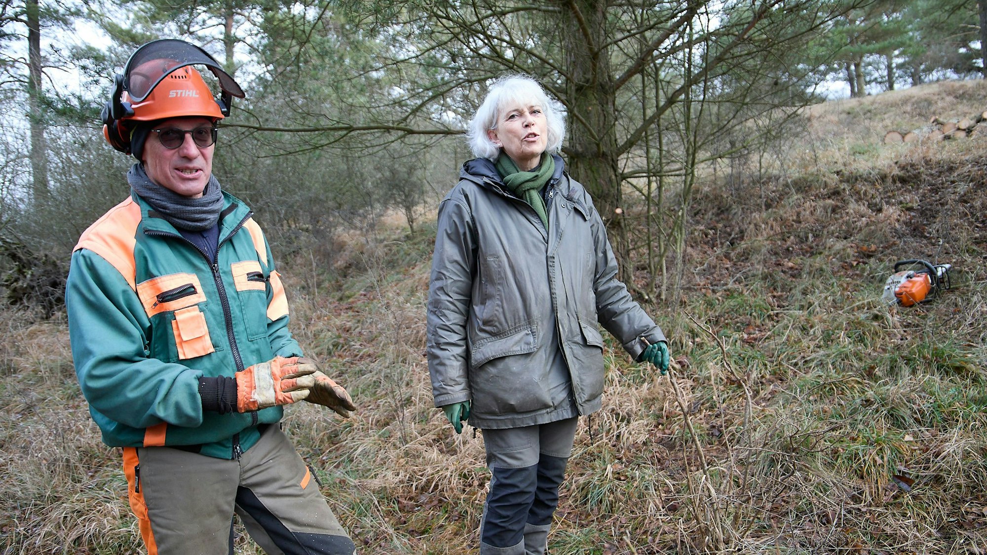 Michael Schulze und Christine Fischer-Ovelhey stehen in einem Hang, rechts im Bild liegt eine Motorsäge.