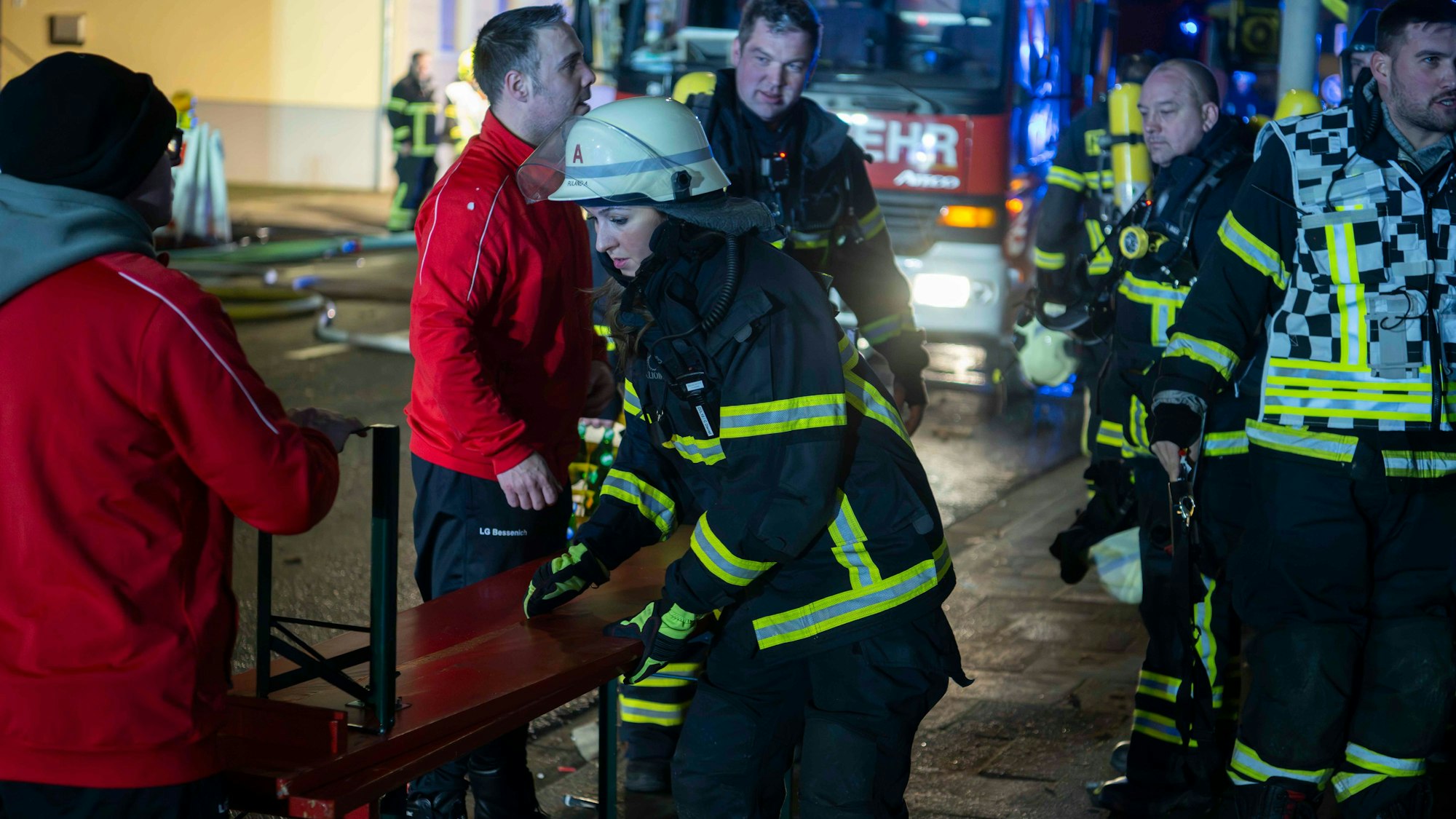 Das Bild zeigt eine Feuerwehrfrau, die eine Bierbank für ihre Kameraden aufbaut.