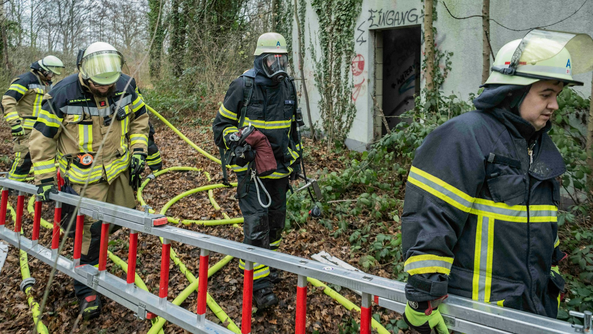 Das Bild zeigt Einsatzkräfte, die den Einsatzort verlassen. Zwei von ihnen tragen eine Leiter.