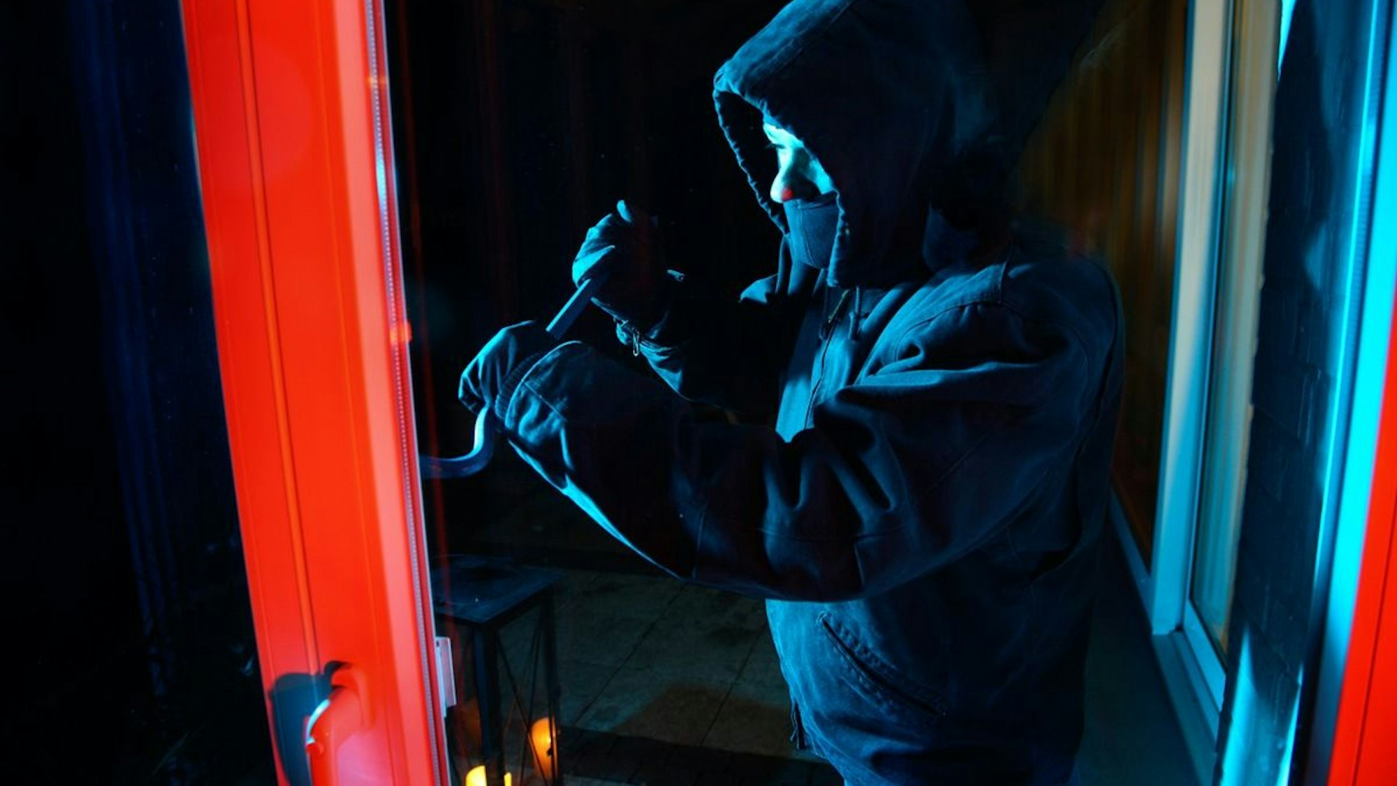 Einbrecher hebeln ein Fenster auf, um in ein Haus einzusteigen.