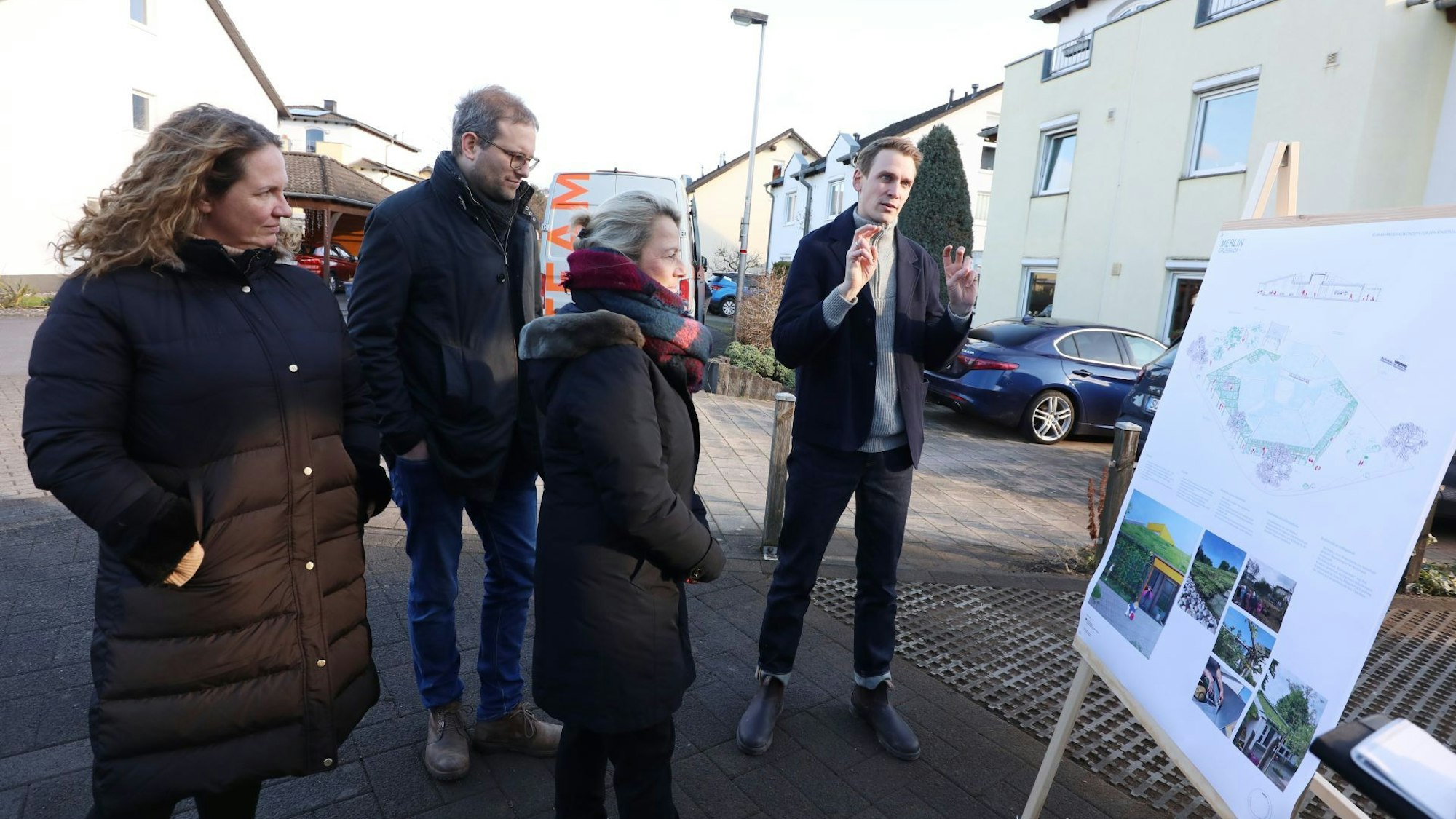 Zwei Frauen und zwei Männer vor einer Tafel mit Plänen und Fotos.
