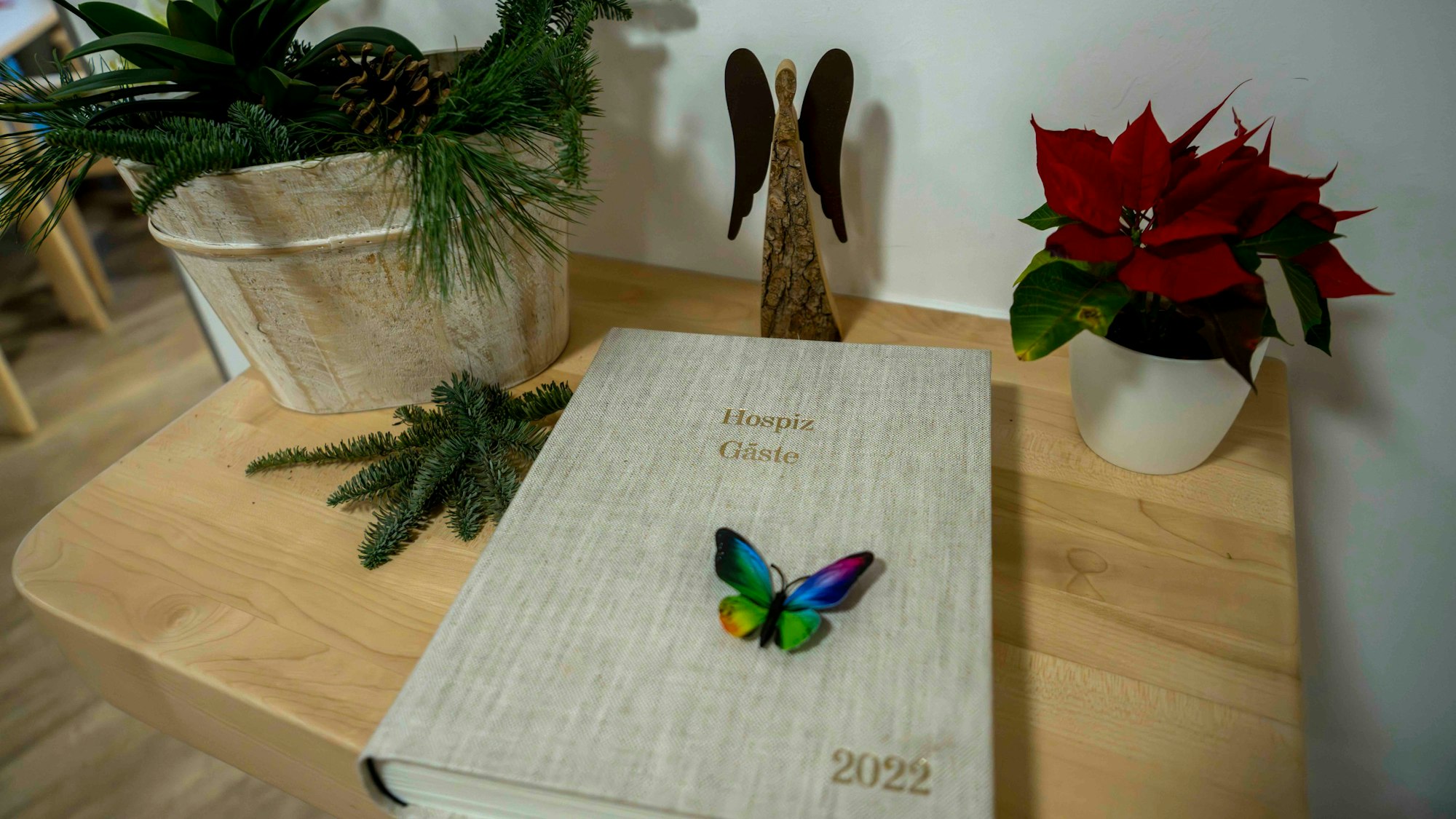 Das Bild zeigt ein Buch, das auf einem Tisch liegt. Zudem sind ein Engel aus Holz und ein Weihnachtsstern zu sehen.