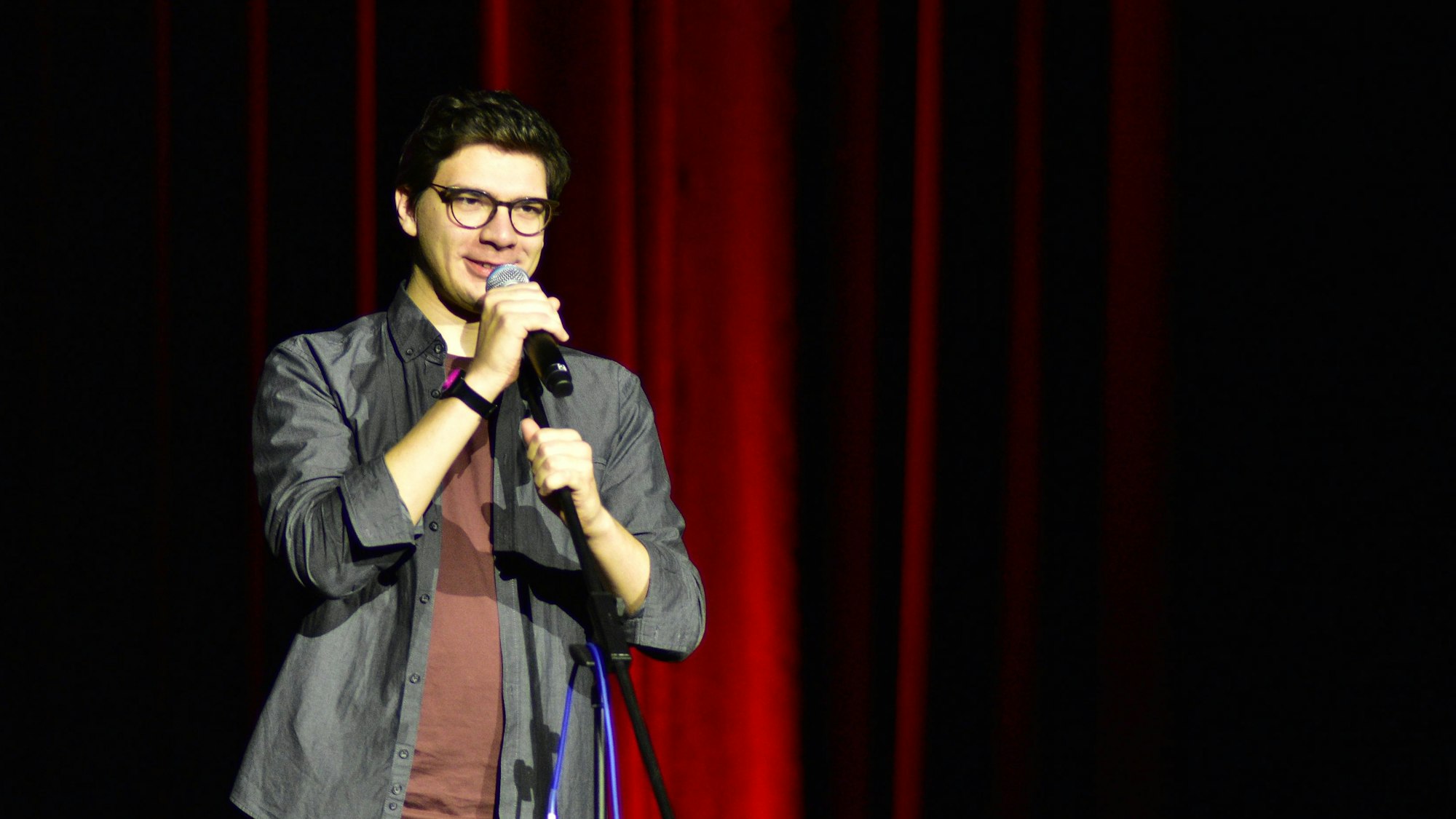 Ein junger Mann steht mit Mikrophon auf einer Bühne