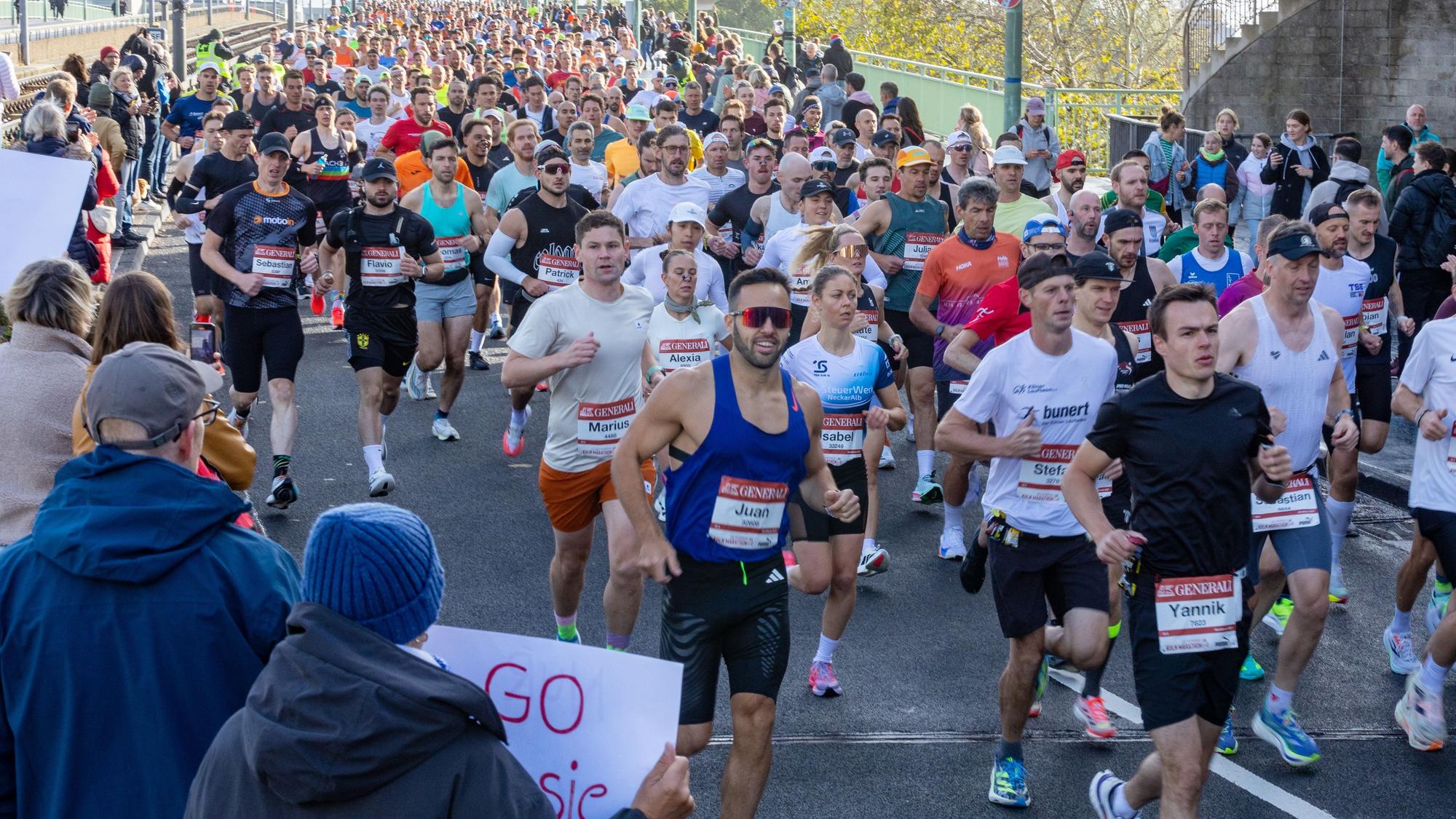 Die Massen laufen nach dem Start des 27. Köln-Marathon auf dem Ottoplatz über die Deutzer Brücke.