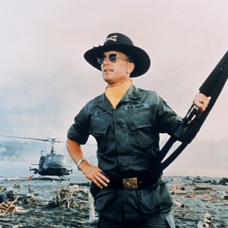 Ein Soldat steht mit Gewehr auf einem Schlachtfeld.