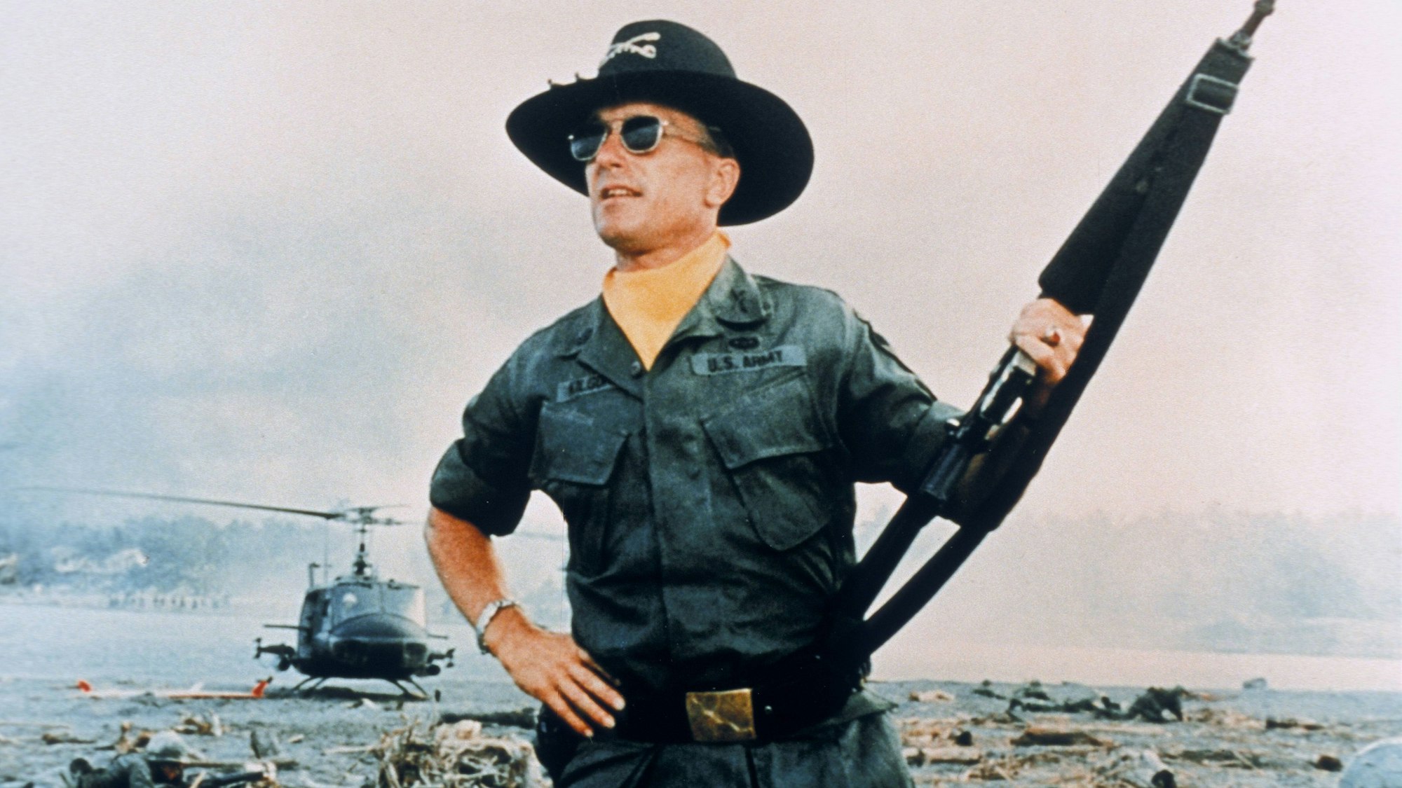 Ein Soldat steht mit Gewehr auf einem Schlachtfeld.