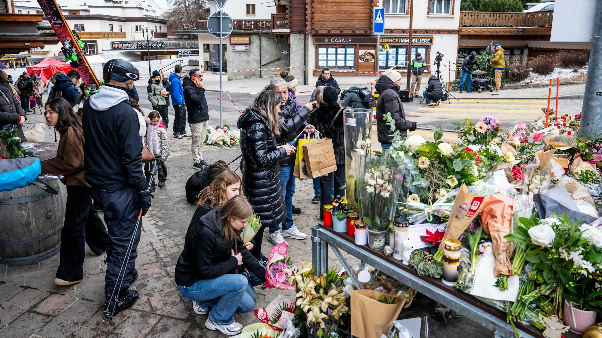 Menschen legen in Crans-Montana Blumen und Kerzen zum Gedenken an die Opfer der Feuertragödie nieder.
