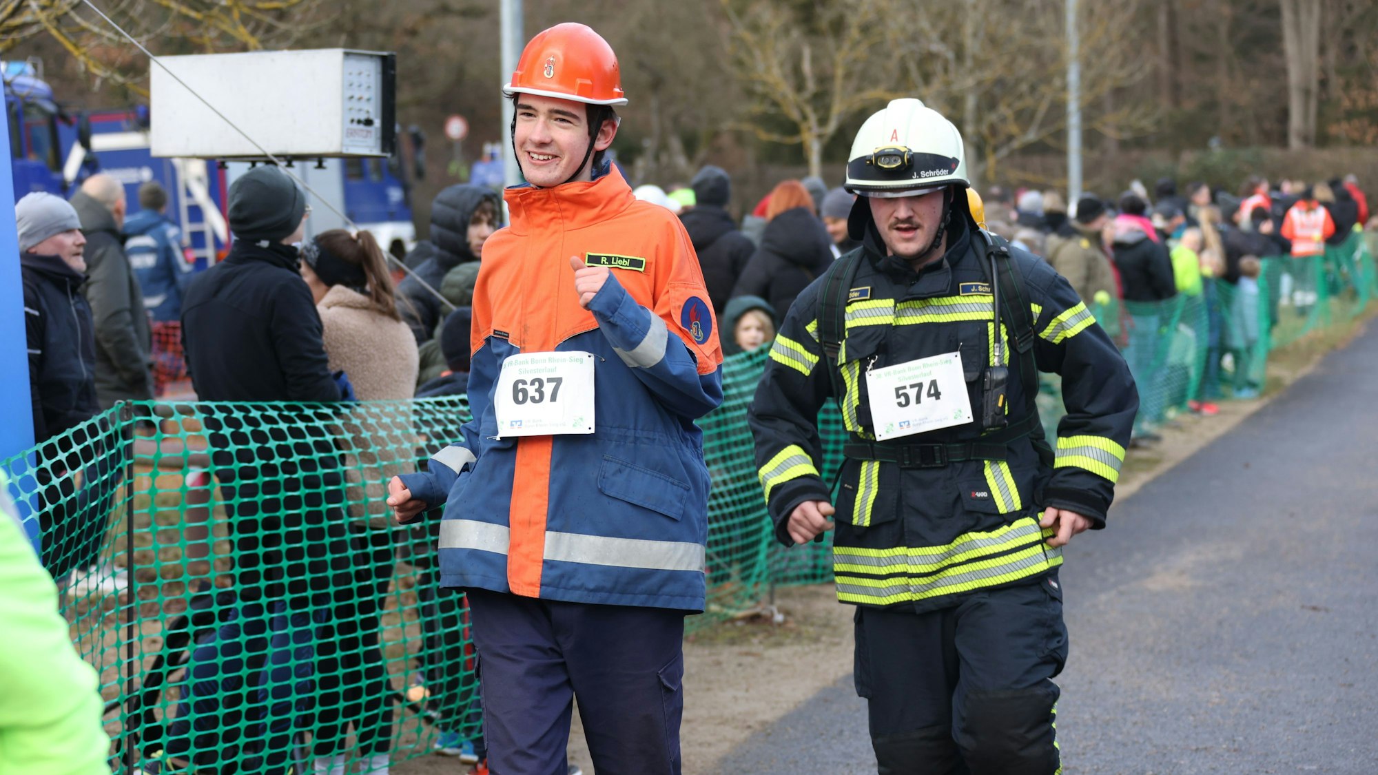 Das Bild zeigt zwei Feuerwehrleute, die die Strecke in Einsatzausrüstung laufen.