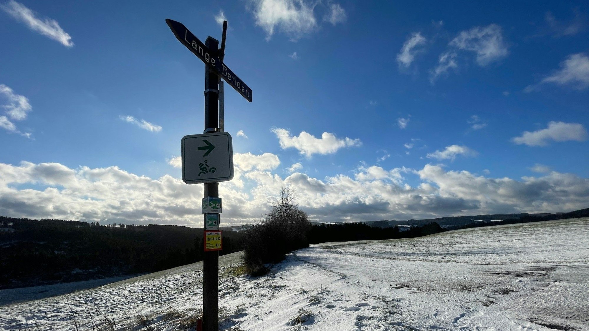 Blick auf die schneebedeckten Flächen und auf einen Wegweiser.