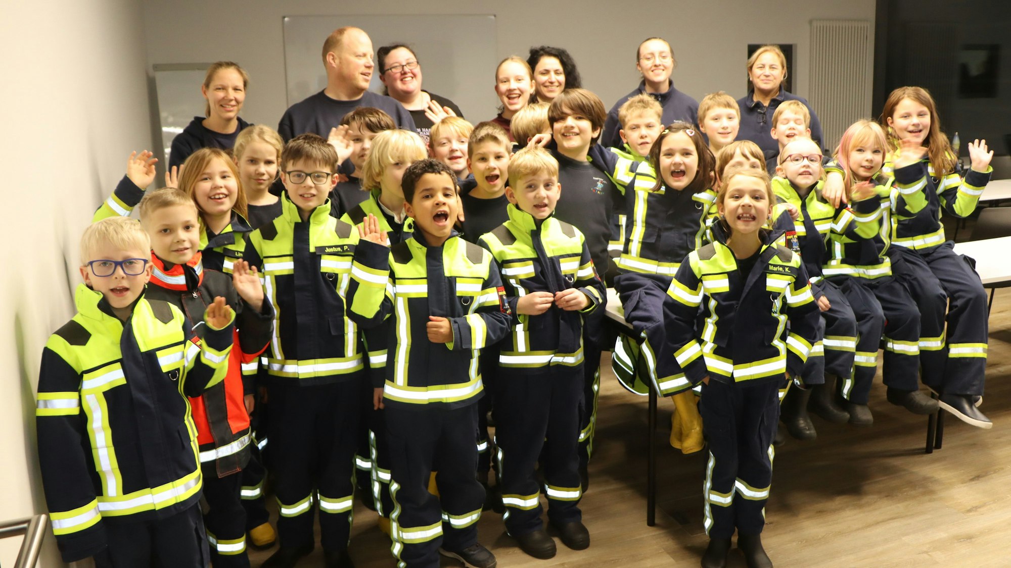 In einem Raum stehen rund 25 Kinder in Feuerwehruniformen und ihre Betreuer.